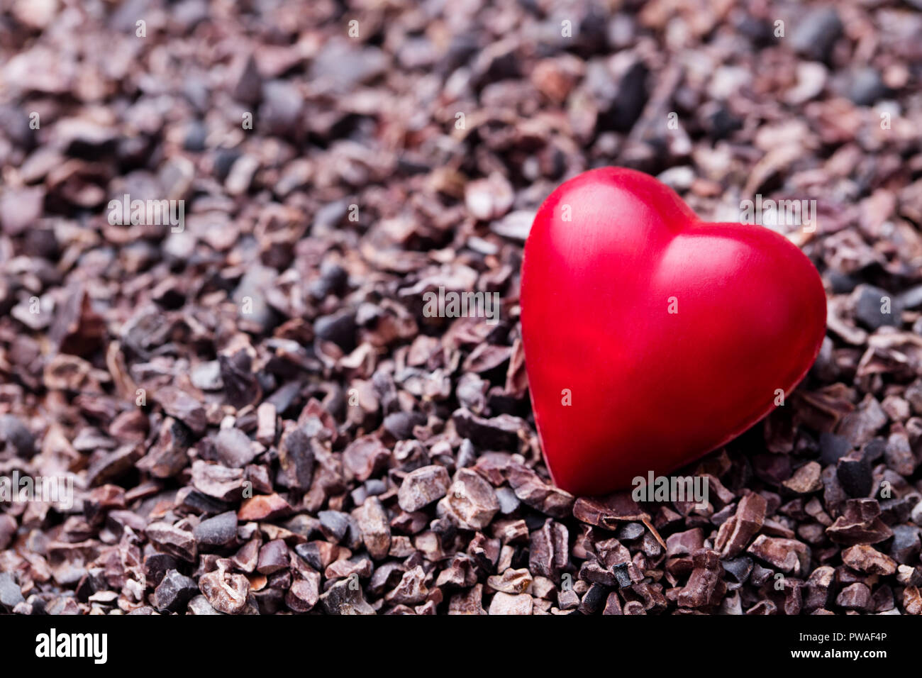 Dulces de chocolate con forma de corazón en puntas de cacao triturada. Cerca. Espacio de copia Foto de stock