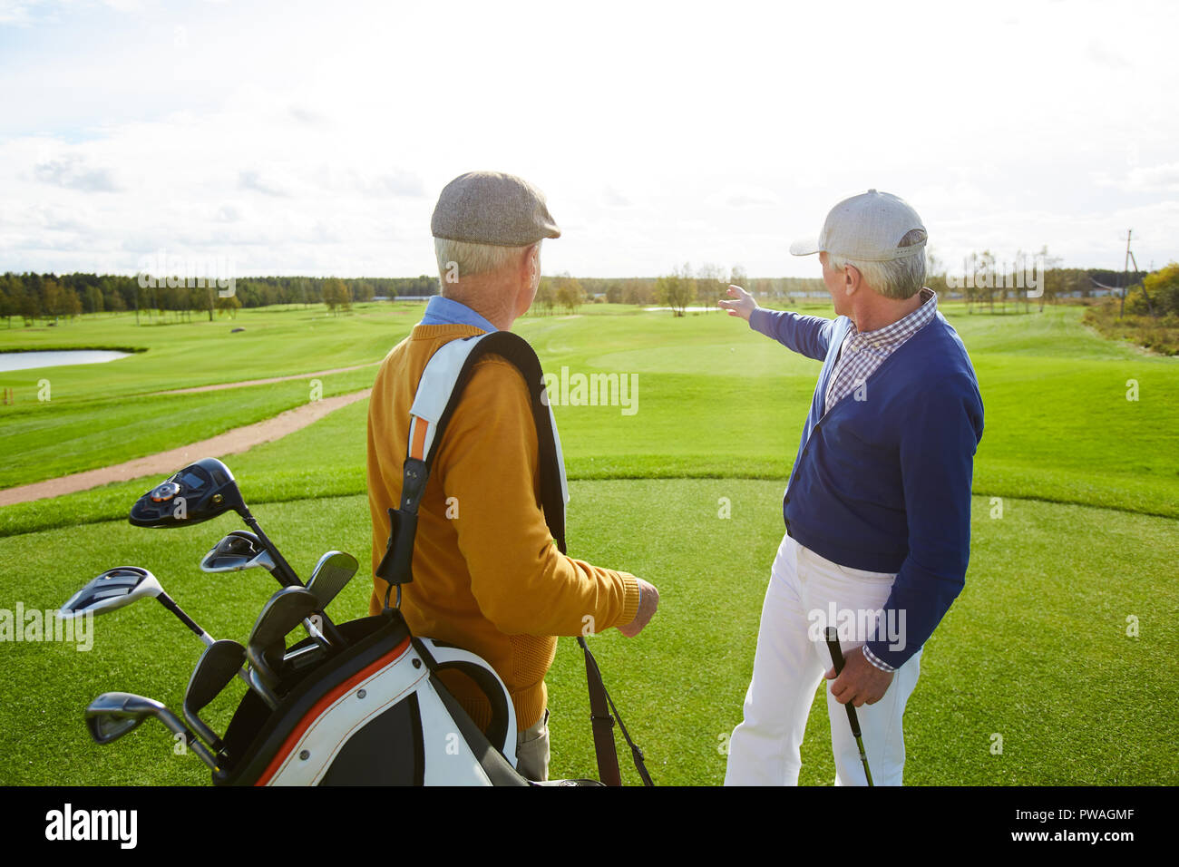 Uno de los jugadores de golf senior mostrando su compañero el lugar donde podrían jugar Foto de stock