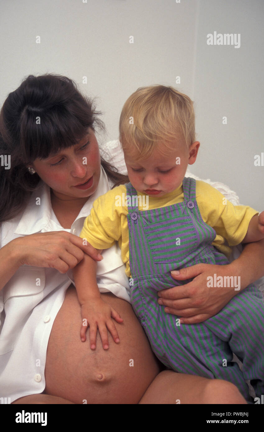 Madre embarazada al hablarle a su niño pequeño sobre el nuevo bebé Foto de stock
