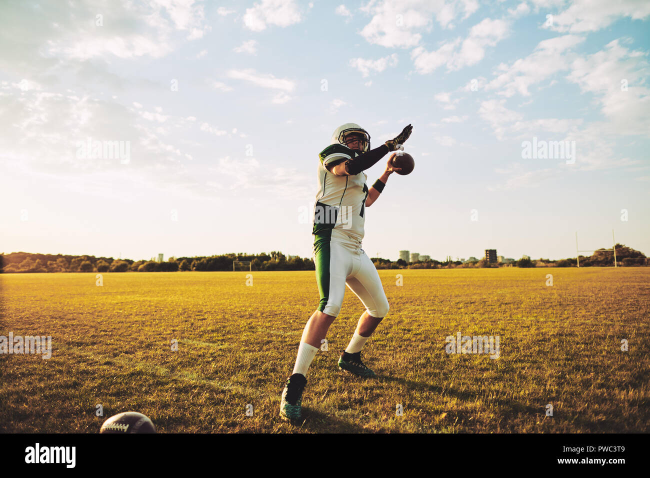 Fútbol americano el mariscal de campo de tirar de un equipo de fútbol durante la práctica de simulacros en un campo de deportes de la tarde Foto de stock