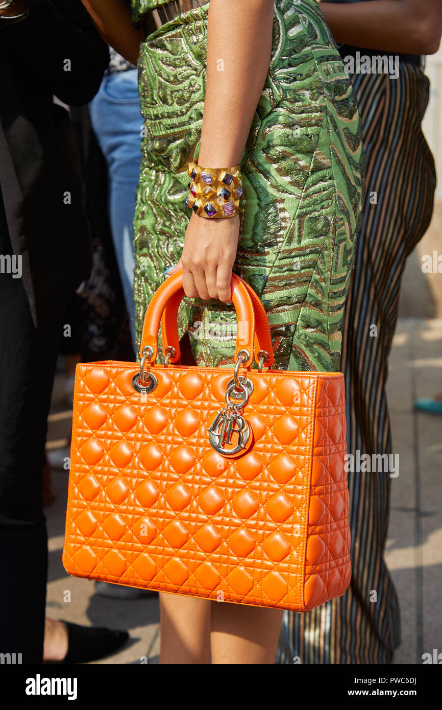 Milán, Italia - 20 de septiembre de 2018: Mujer con naranja bolso Dior,  pulsera de oro con