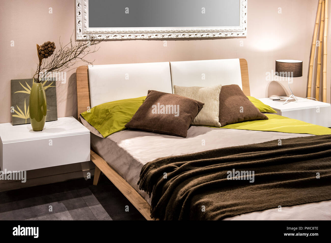 Interior del dormitorio con cuatro almohadas en la cama y el espejo en la pared Foto de stock