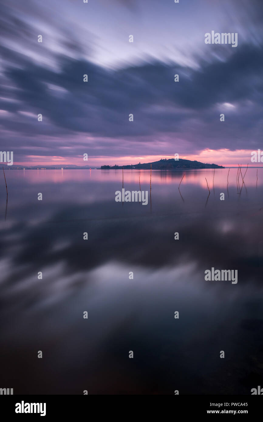 Puesta de sol sobre el Lago Trasimeno, día nublado. Como el reflejo del espejo. Paisaje italiano. Foto de stock