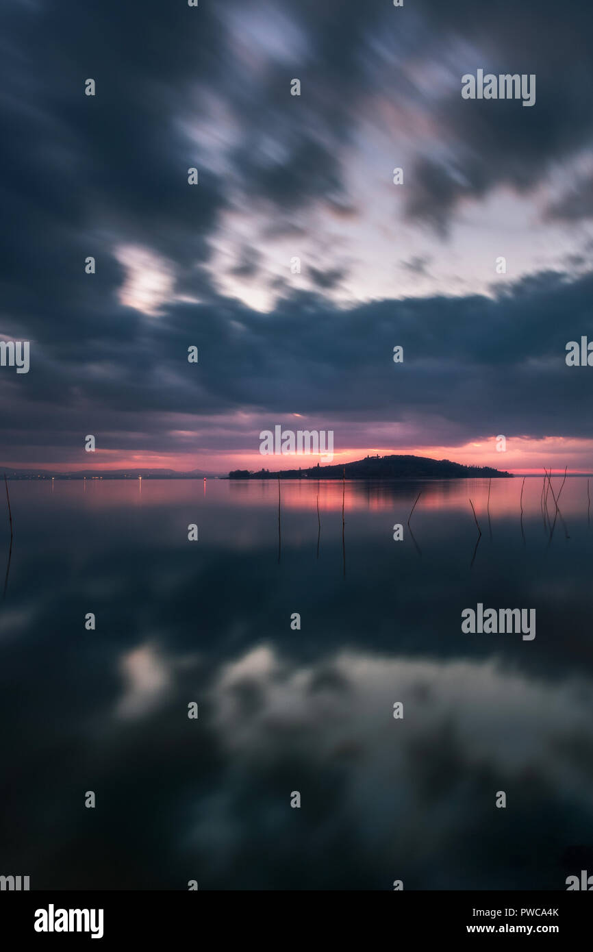 Puesta de sol sobre el Lago Trasimeno, día nublado. Como el reflejo del espejo. Paisaje italiano. Foto de stock