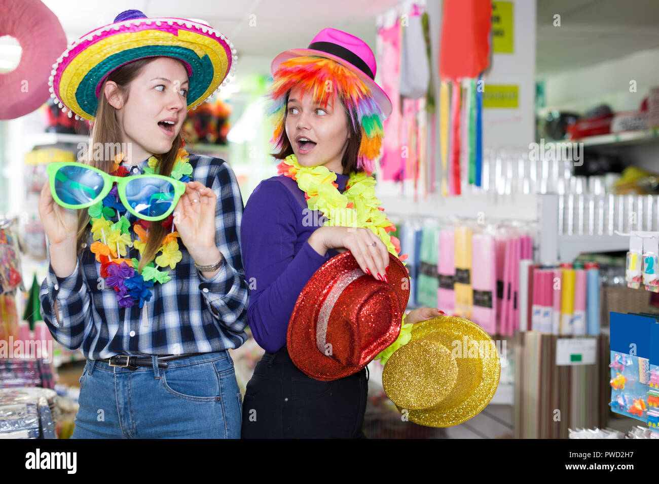 Las niñas alegres juntos de compras, buscando sombreros divertidos en la  tienda de fiesta trajes y accesorios Fotografía de stock - Alamy