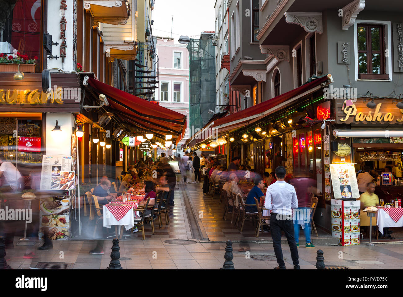 Restaurantes con cenas al aire libre en el crepúsculo como la gente camina pasado, Estambul, Turquía Foto de stock