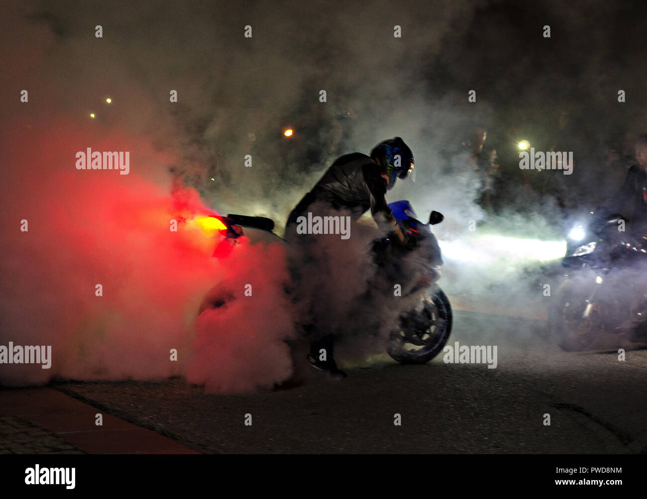 А espectacular moto show nocturno con un montón de humo y un neumático de neumáticos. Muchos de adrenalina. Iluminación roja y blanca. Foto de stock