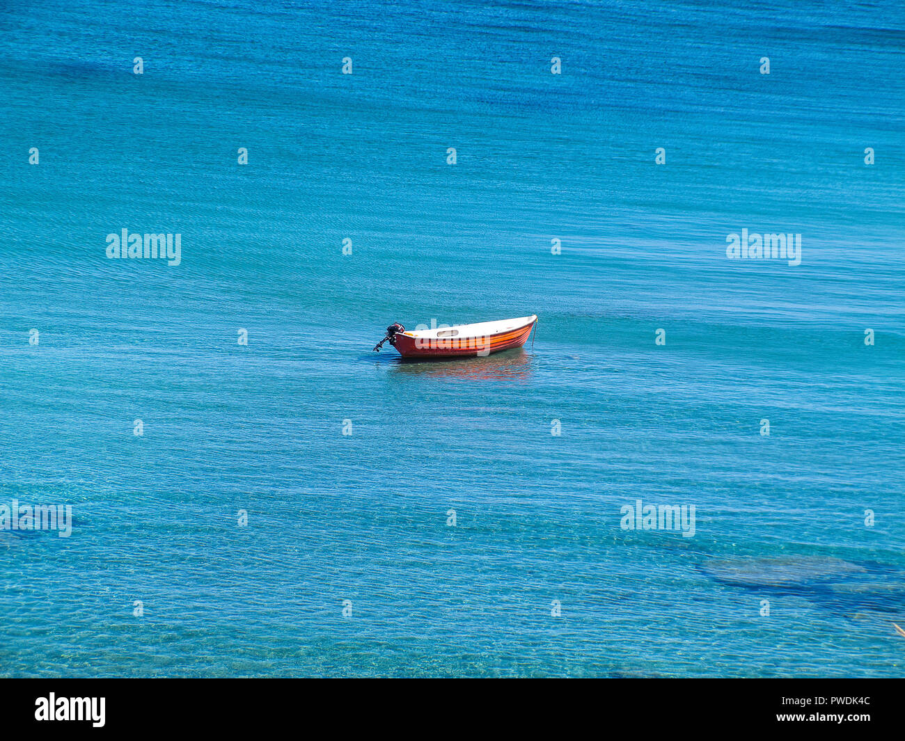 Little Red Boat, sin nadie a bordo, en el medio del mar azul de Calabria, en la región oriental de costa italiana Foto de stock
