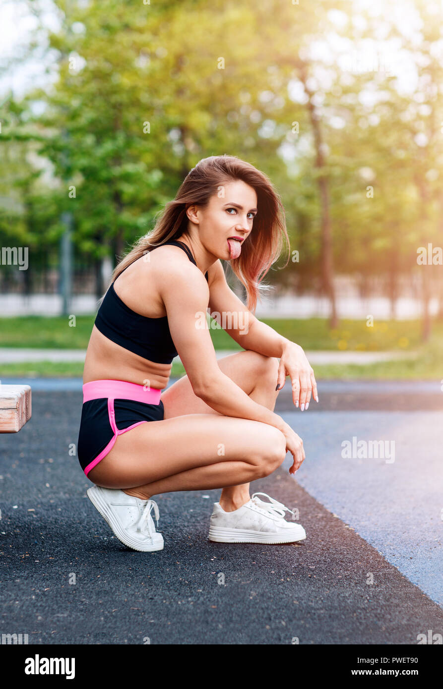 Mujer deportiva con perfecto cuerpo atlético muestra lengua Foto de stock