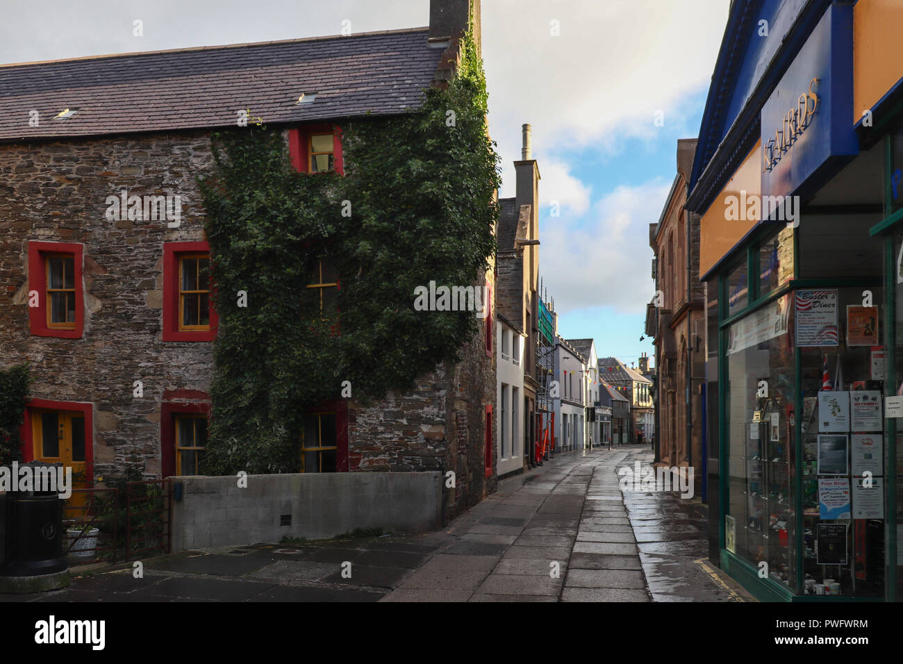 En la mañana del domingo en Albert Street en Kirkwall, Orkney, Escocia, con el sol tan solo mirar a través de los edificios; coloridos blue sky, la luz dorada. Foto de stock