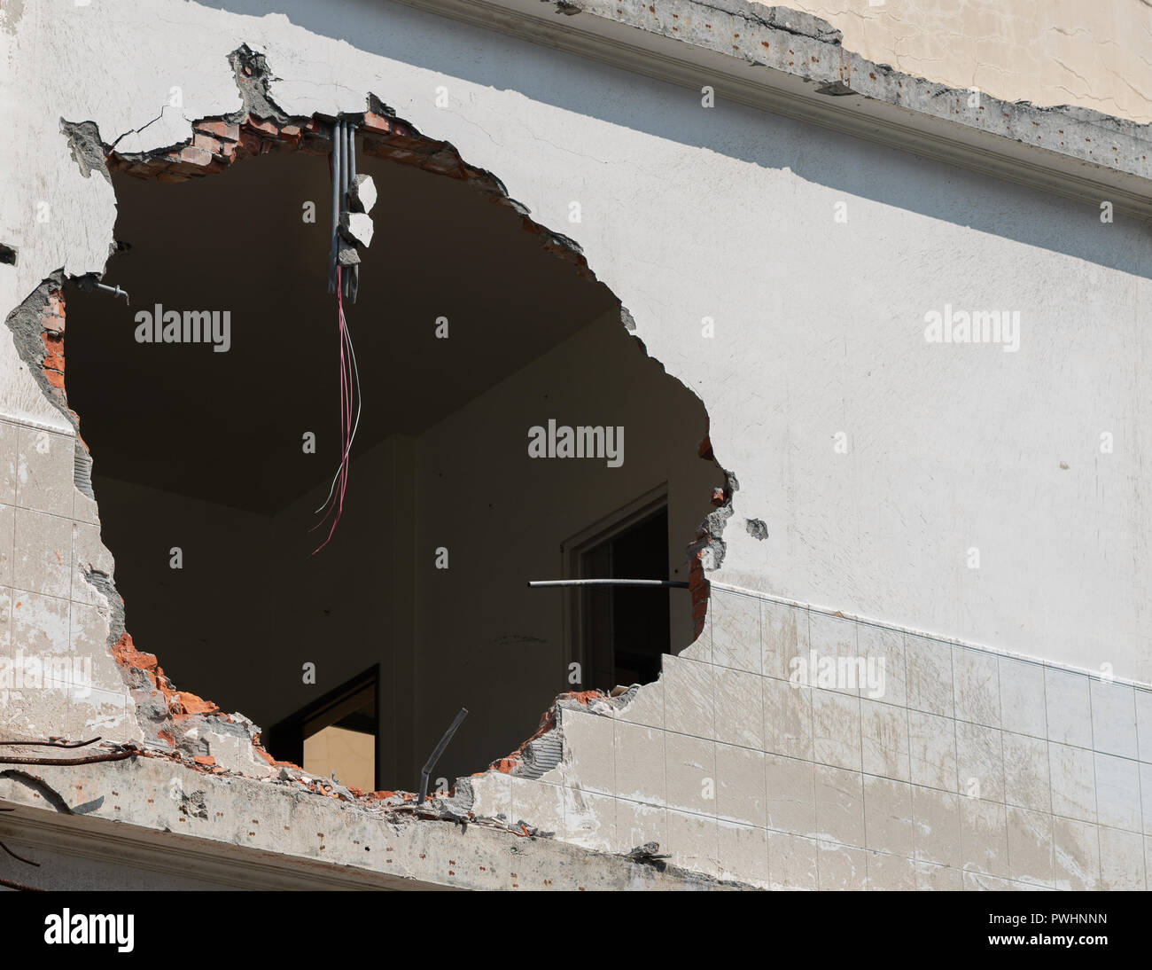 Enorme agujero con cables colgando en una pared del edificio y espacio de copia Foto de stock