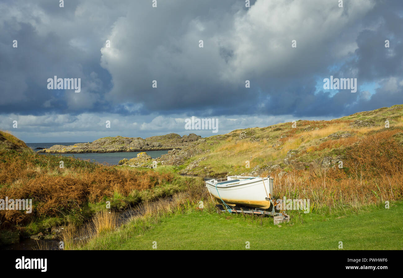 Escocia, pequeña embarcación de pesca blanca atada sobre tierra seca en áreas remotas de la península de Ardnamurchan en las Highlands escocesas. Pesado, cielos nublados. Foto de stock
