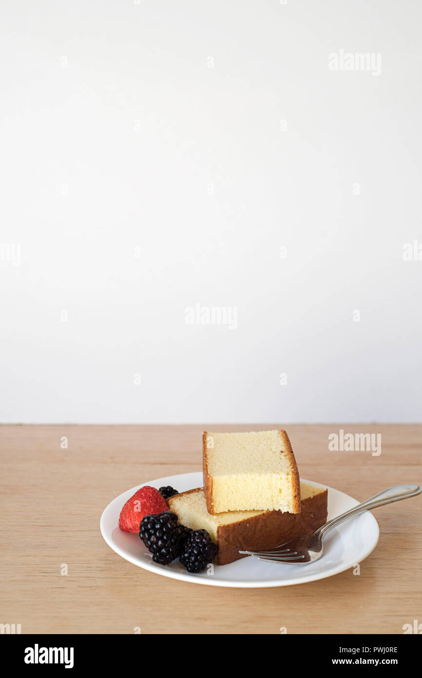 Plano amplio de pan de torta cortes mientras sirve en un plato en frente de un fondo de luz vertical Foto de stock
