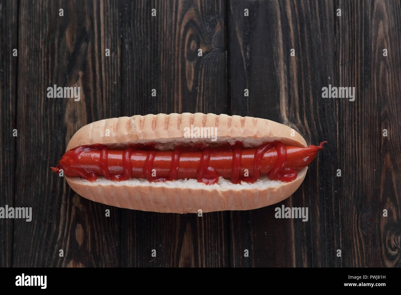 Hot Dog con salchicha ahumada en madera oscura de fondo.foto con Foto de stock