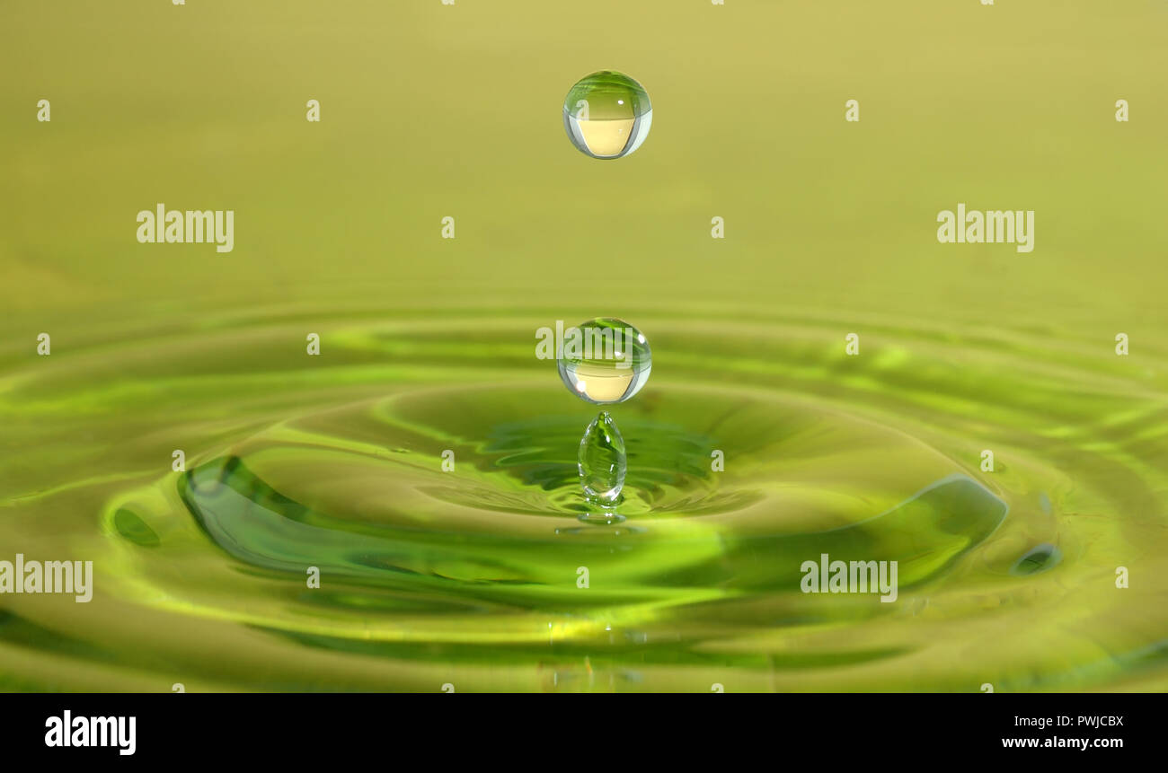 Splash closeup. Gota de lluvia caen sobre la superficie de agua verde. Foto de stock