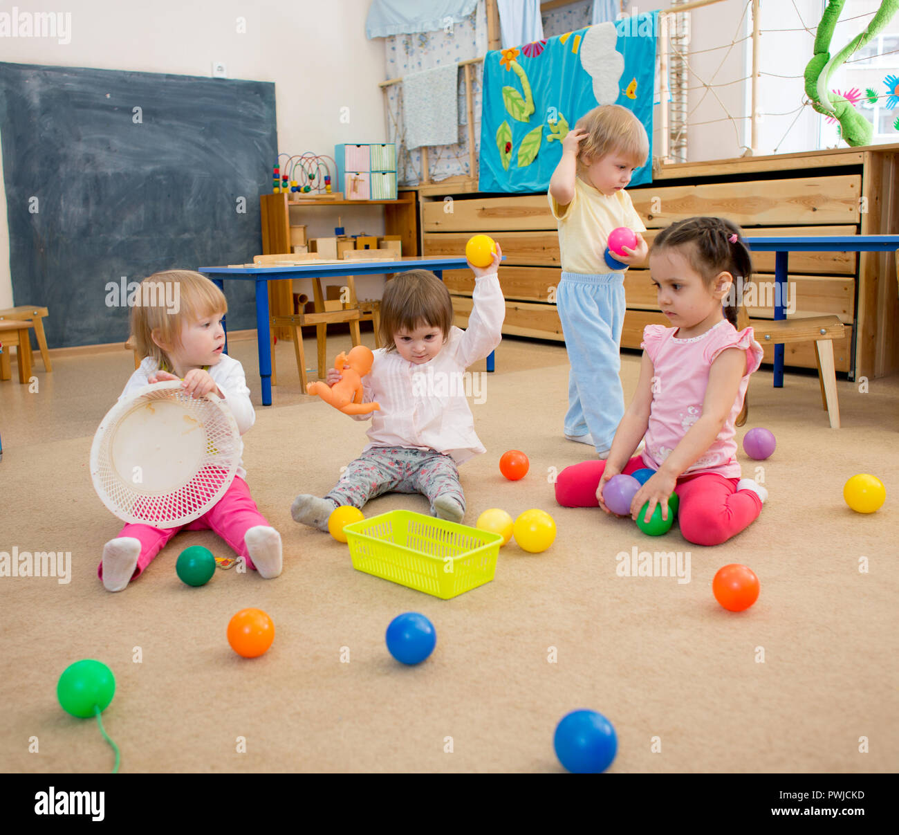 Un grupo de niños jugando a las bolas en el jardín de infantes o guardería Foto de stock