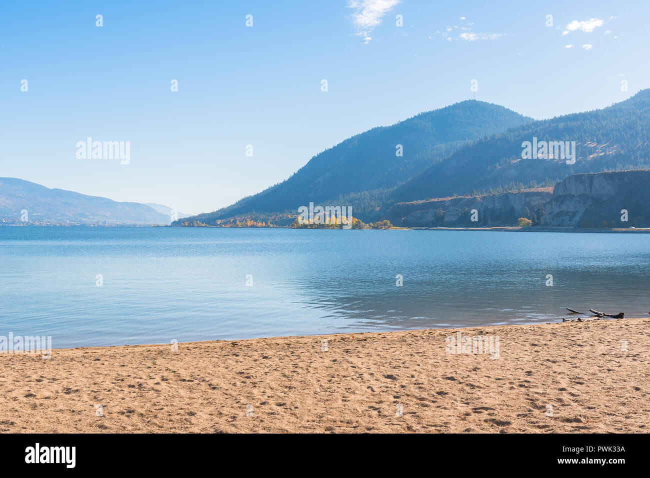 Lago con playa de arena, montañas y cielo azul Foto de stock