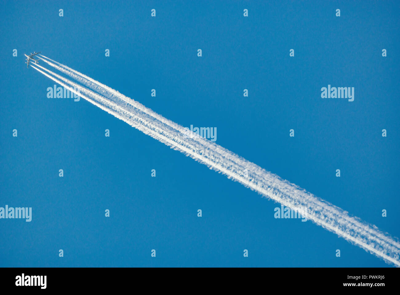 Una larga estela de avión, sobre fondo de cielo azul. Foto de stock