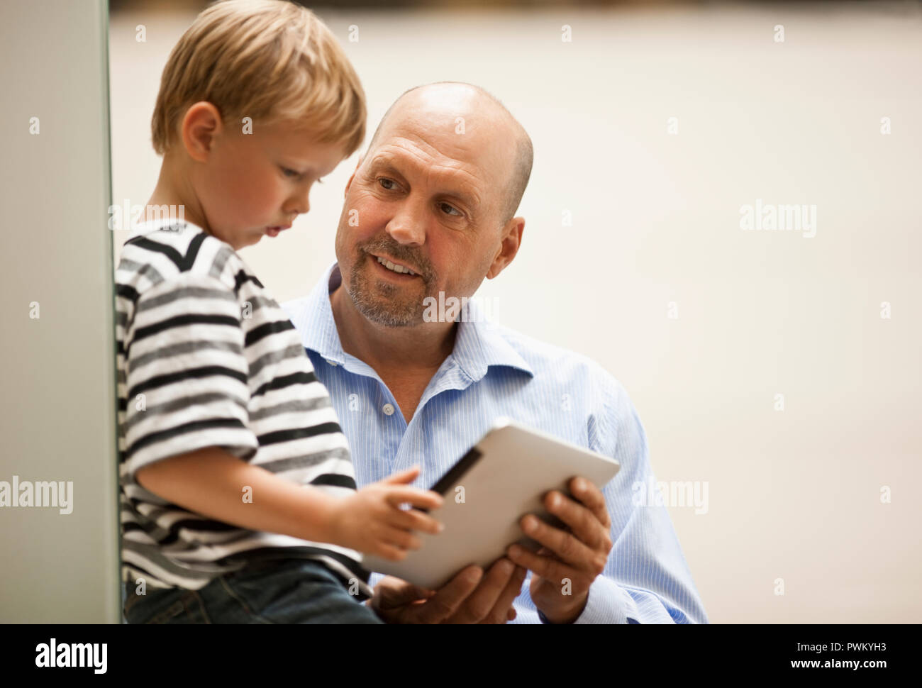Un padre y su hijo mirar una pantalla de Ipad. Foto de stock