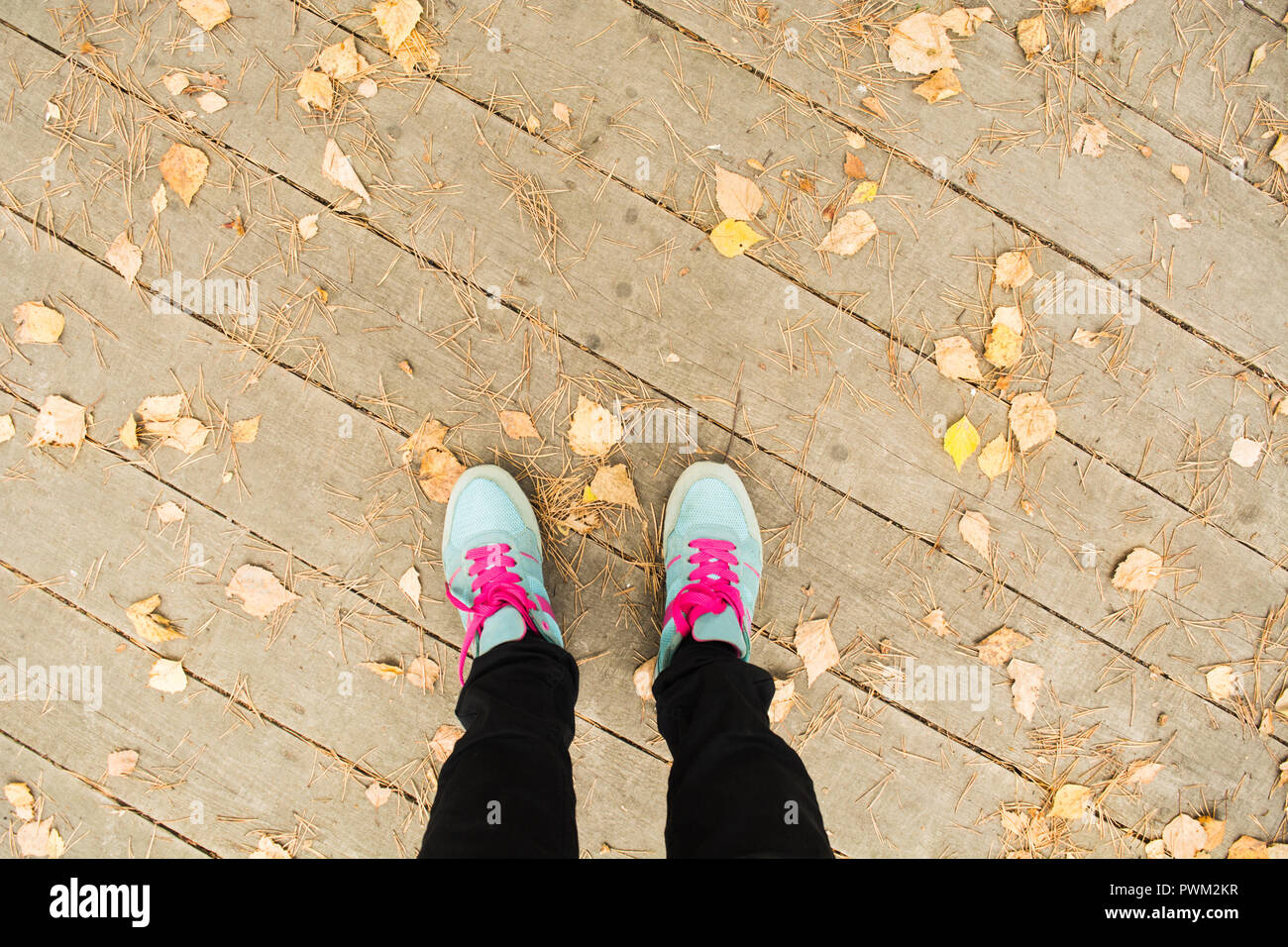 Los pies femeninos en el deporte Botas azul, quedándose en una plataforma  de madera en el parque de otoño con la caída de las hojas, laicos plana  Fotografía de stock - Alamy