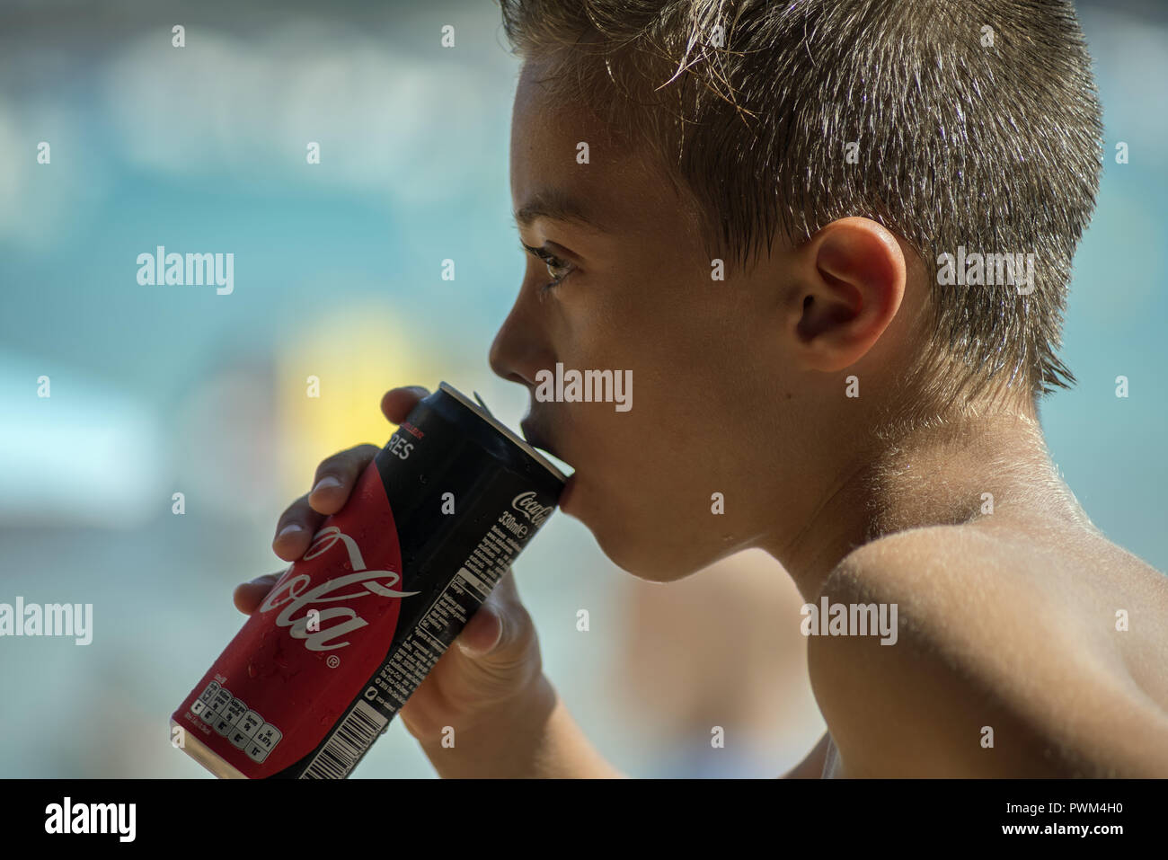 Un muchacho delgado es beber una Coca-Cola puede. Foto de perfil y en close-ups. Playa de Santa Giulia en Córcega. Pije Chłopiec puszki Coca-Colę z. Foto de stock
