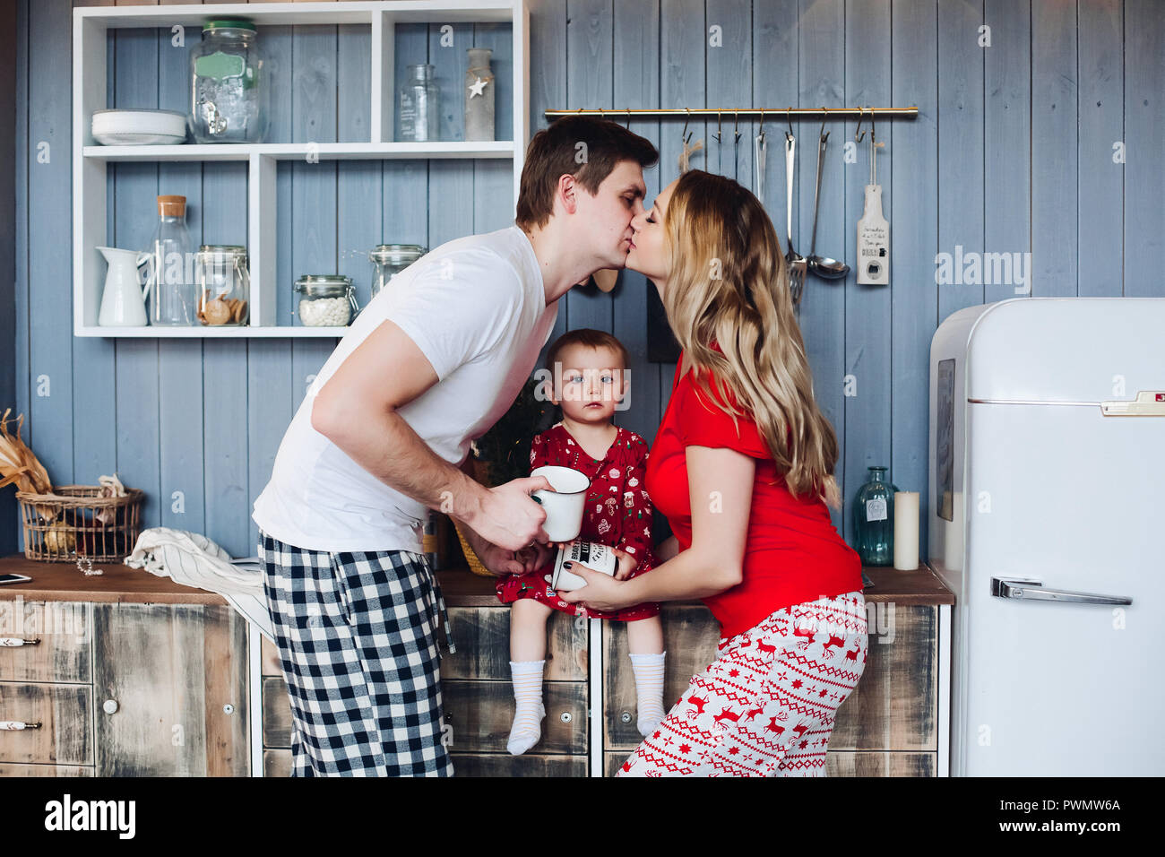 Familia Feliz Navidad vestían pijamas cocinar juntos en la elegante cocina  de madera con una hija pequeña. Hermosa mamá, papá guapo buscando  mutuamente Fotografía de stock - Alamy