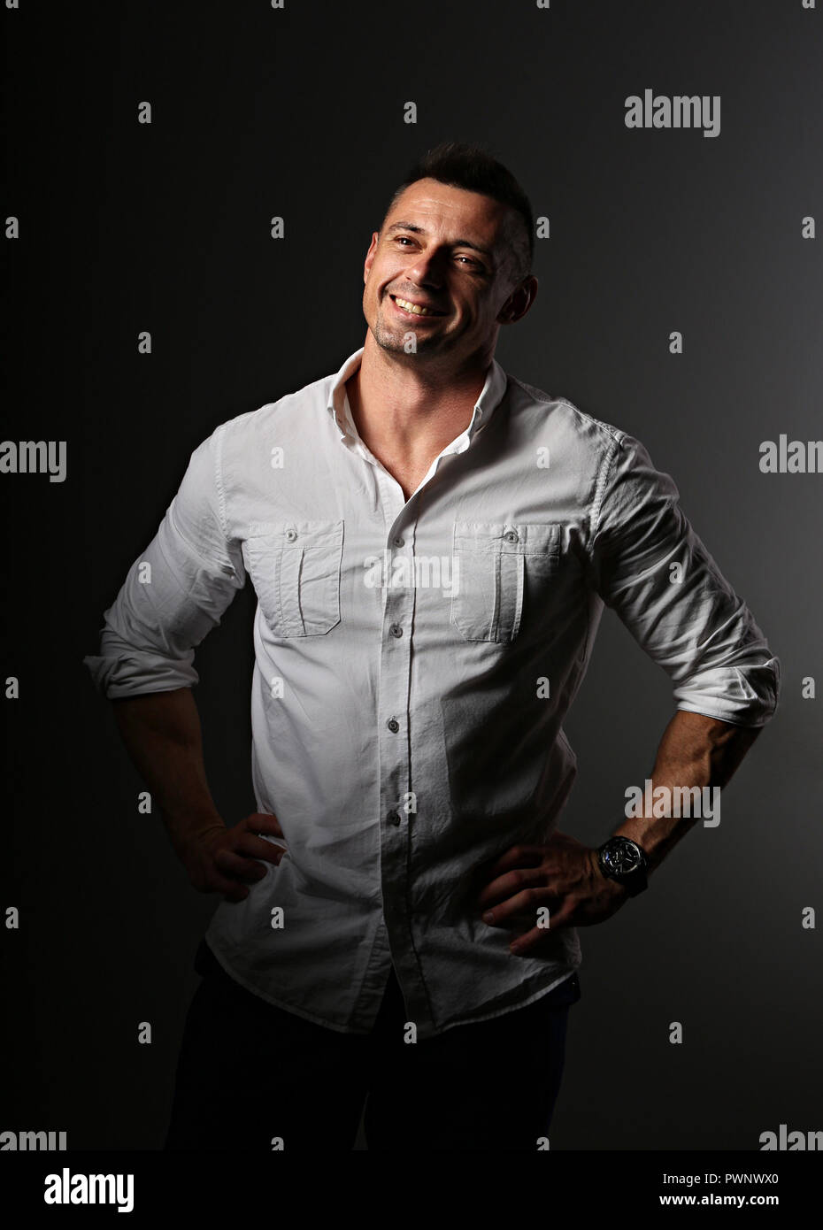 Apuesto hombre de negocios buscando con happy sonriente en blanco de estilo camisa  gris oscura sombra de fondo. Closeup retrato Fotografía de stock - Alamy