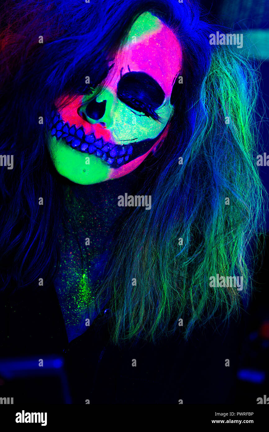 Mujer con la cara pintada con neón maquillaje con diseño de una calavera  para halloween Fotografía de stock - Alamy