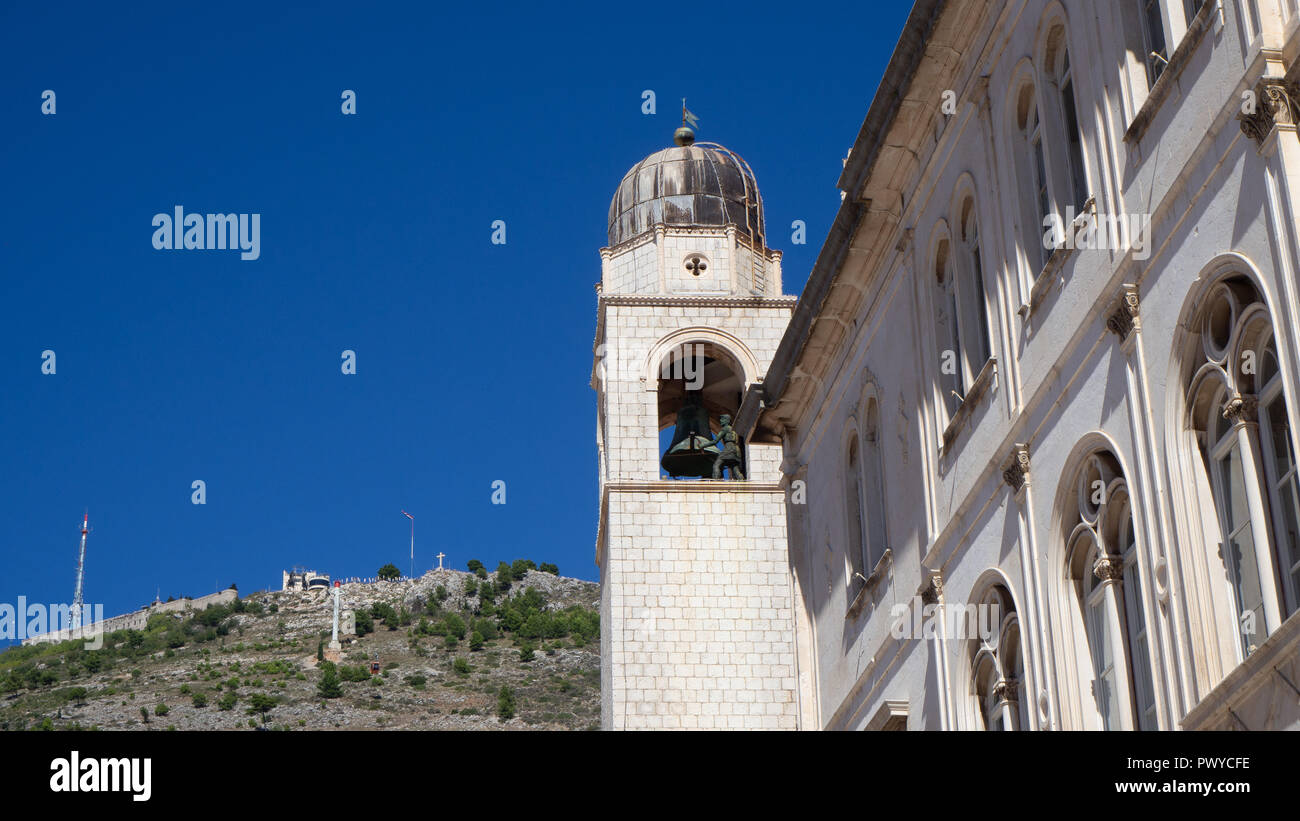 La torre del reloj de Dubrovnik con la montaña Srd en el fondo Foto de stock