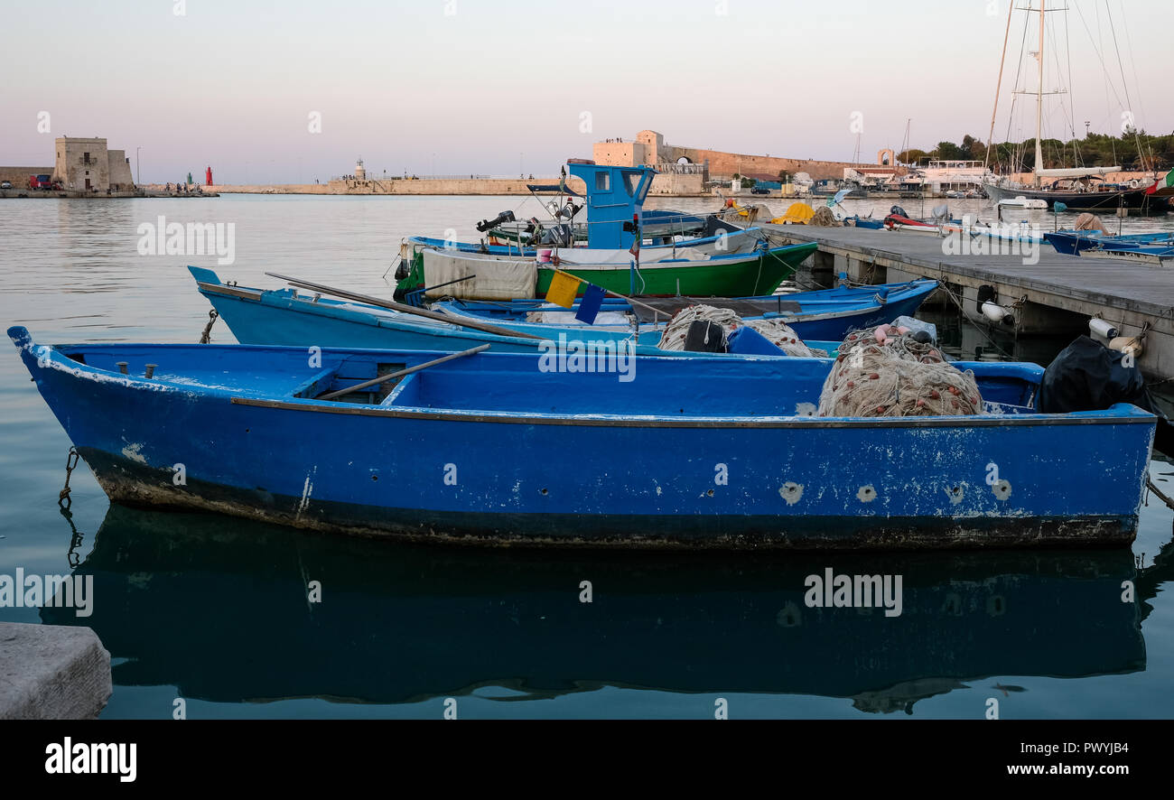 El pintoresco puerto pesquero de Trani, centro histórico medieval en Apulia, en el sur de Italia. Coloridos botes de pesca en primer plano. Foto de stock