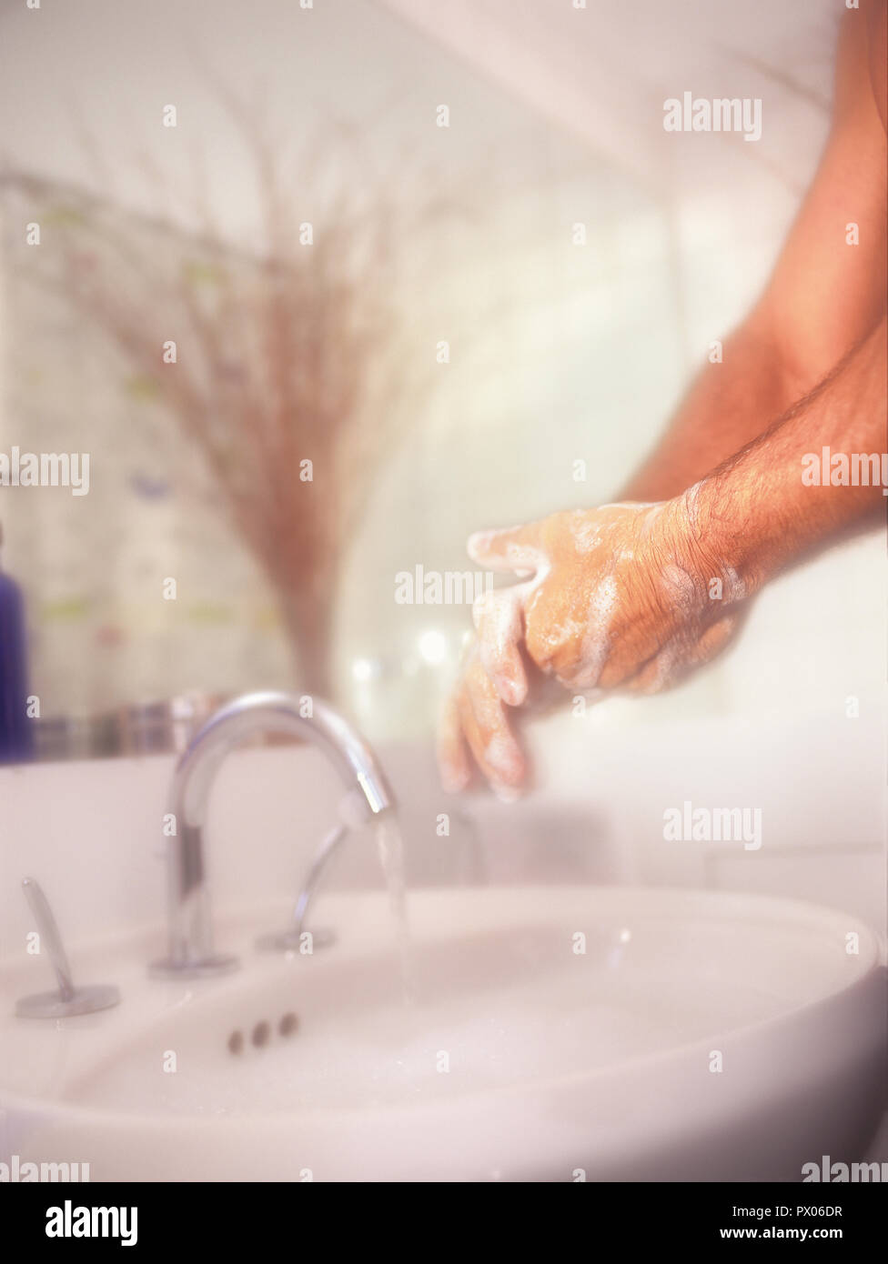 Hombre fregado y lavado de las manos con vigor contra un fondo suave en el baño. Foto de stock
