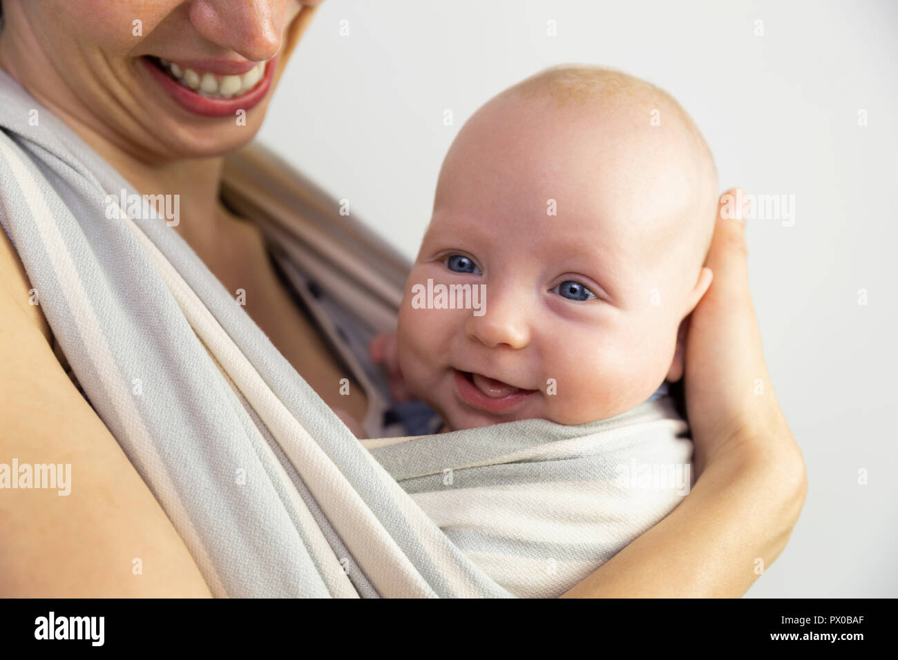 Feliz bebé y a la madre. Bebé cerca de la madre en un cabestrillo. Foto de stock