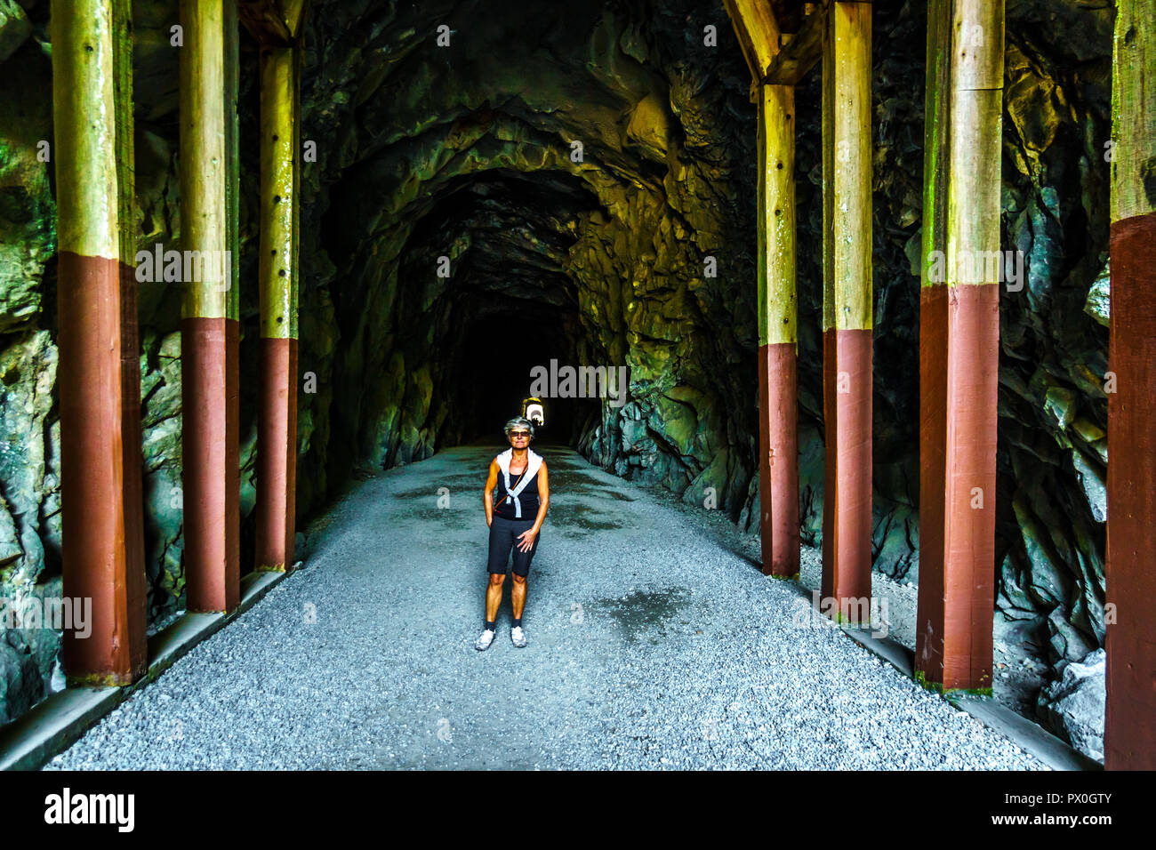 Mujer caminando en el Othello túneles que fueron talladas por la Coquihalla cañón para el ahora abandonado Kettle Valley Railway en esperanza, BC, Canadá Foto de stock