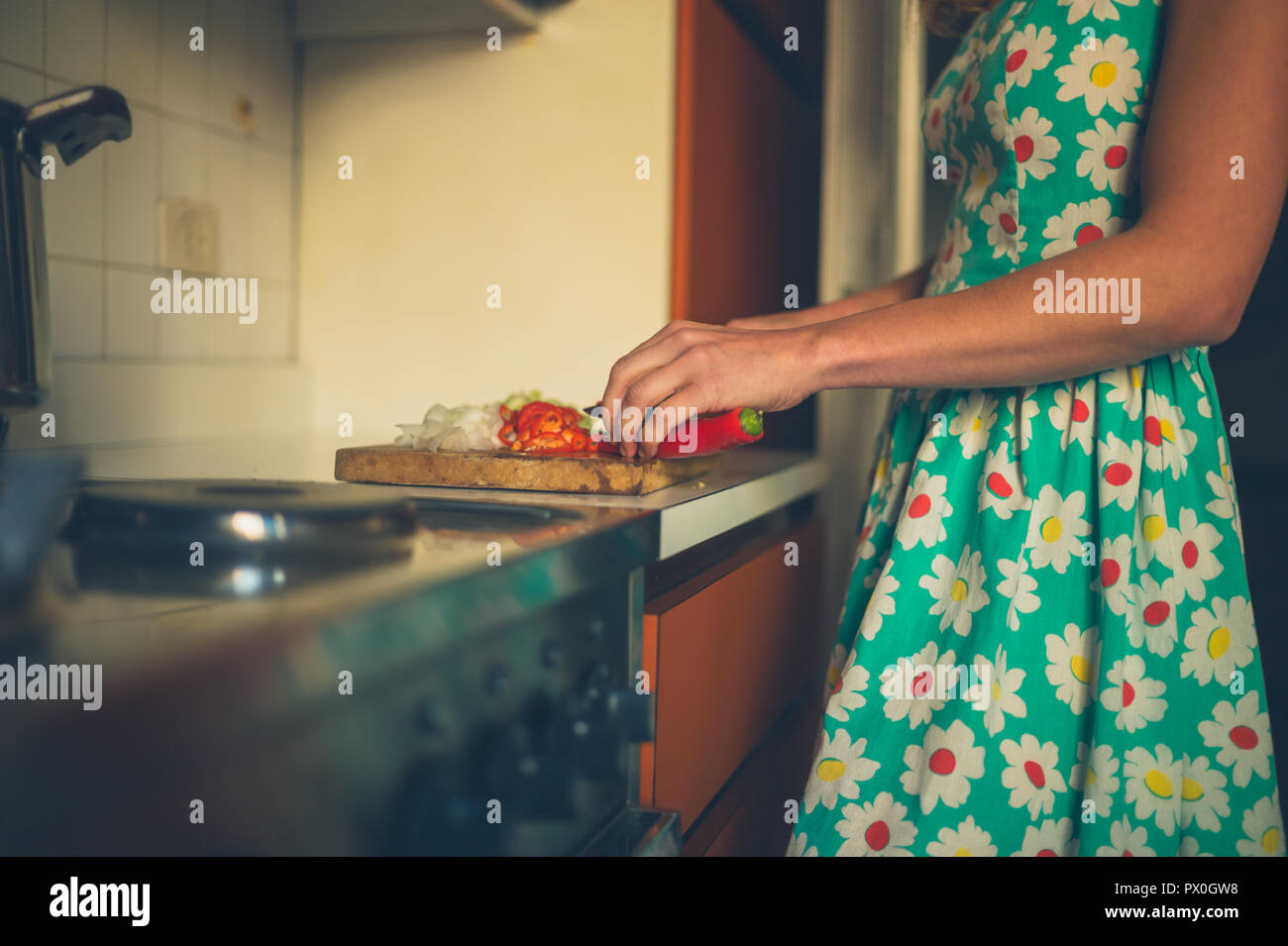 Una mujer joven está cocinando la cena en su cocina Foto de stock