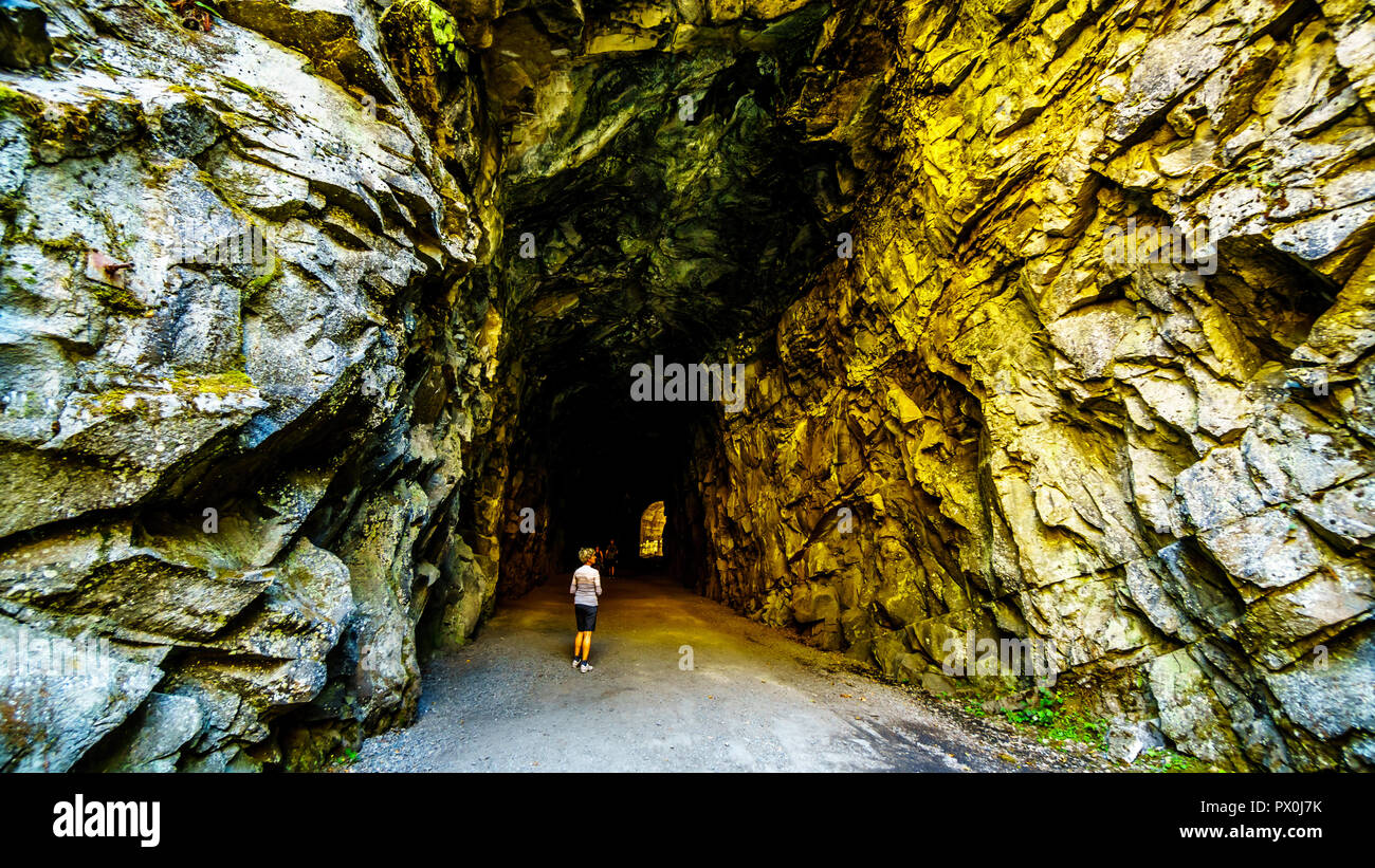 Los turistas que caminan en el Othello túneles que fueron talladas por la Coquihalla cañón para el ahora abandonado Kettle Valley Railway en esperanza, BC, Canadá Foto de stock