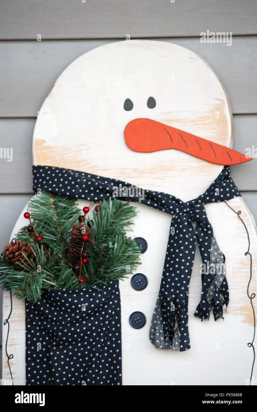 Un muñeco de madera decoración de invierno con una bufanda de tela y  bolsillo lleno de invierno, piñas y bayas verdes Fotografía de stock - Alamy