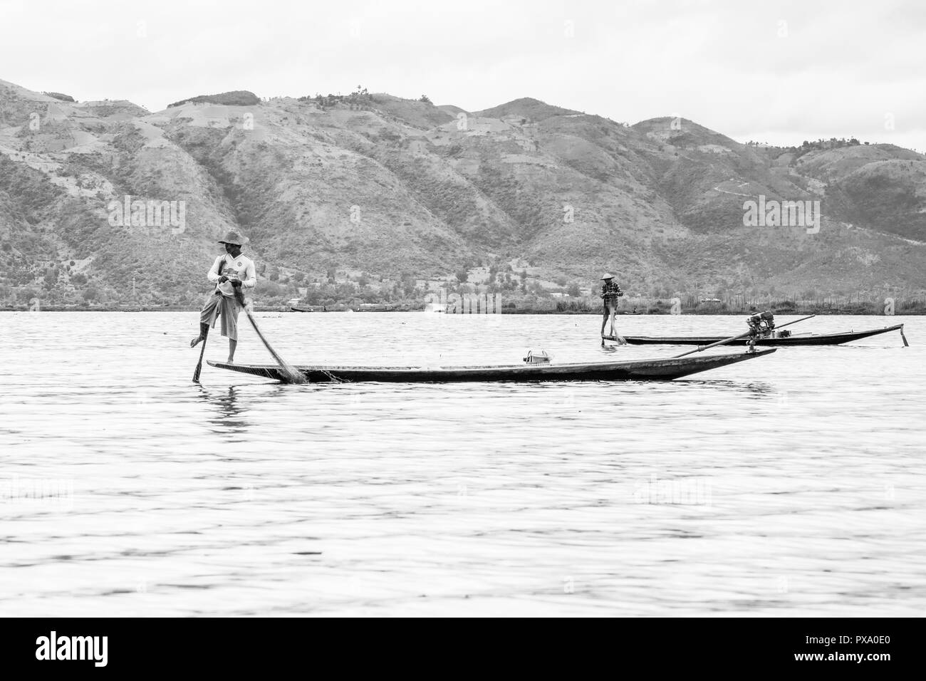 Viajes: jóvenes birmanos pescador local vistiendo la camiseta del Manchester United, el equilibrado y el barco de la dirección con su pie en el Lago Inle, Birmania, Myanmar, Asia Foto de stock