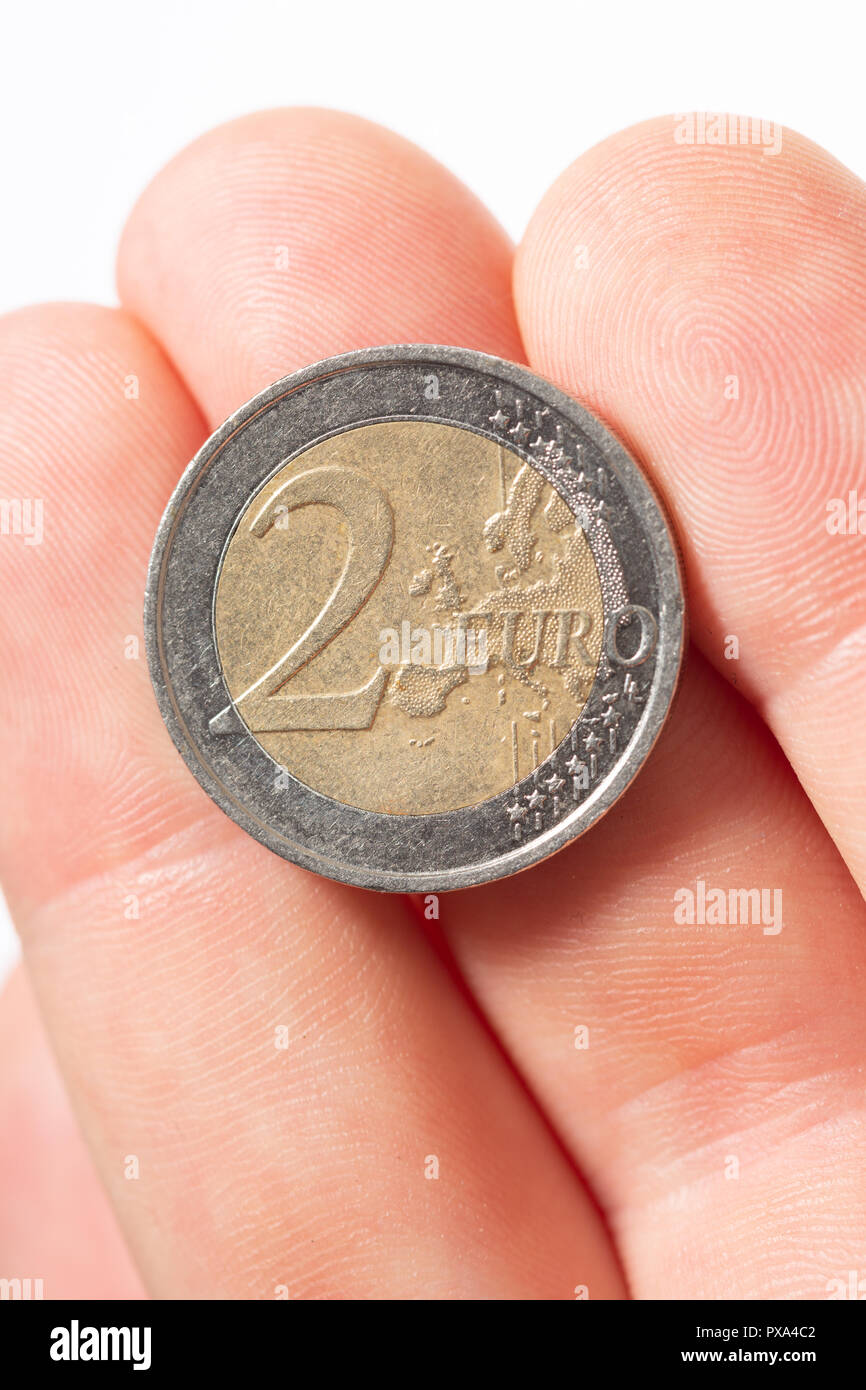 Topview cerca de una moneda de dos euros en hombres caucásicos dedos sobre un fondo blanco. Foto de stock