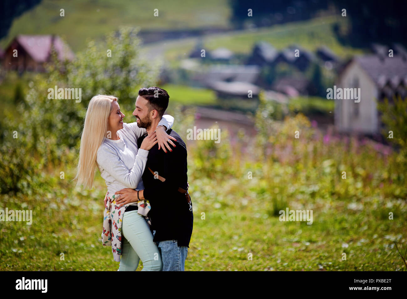 Vacaciones de verano, gente, amor y dating concepto - pareja feliz abrazando a lo largo de luces verdes antecedentes Foto de stock