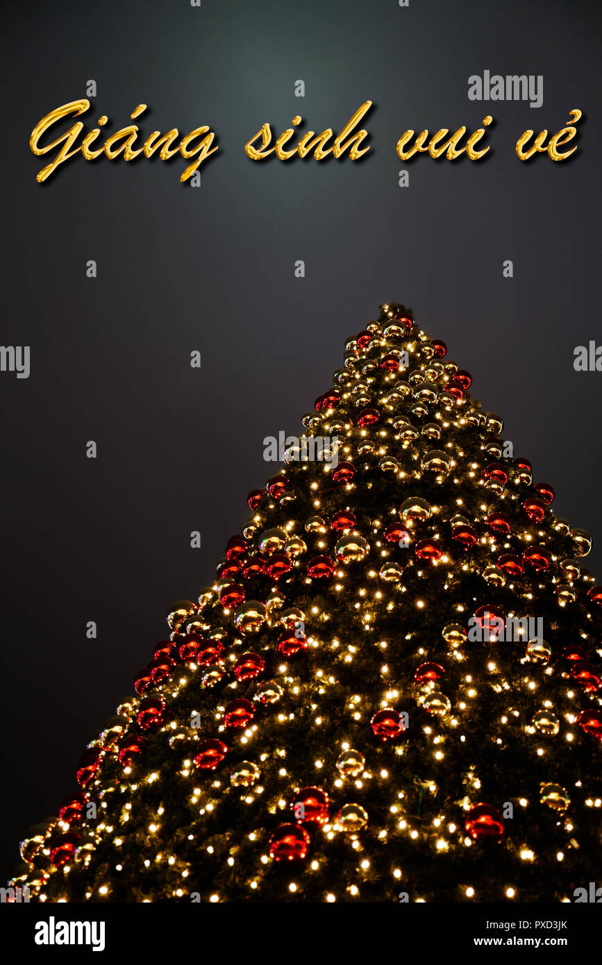 Un árbol de Navidad con adornos rojos y dorados. El texto "Giáng vietnamita Sinh vui vẻ" significa "Merry Christmas". Una perfecta tarjeta de felicitación. Foto de stock