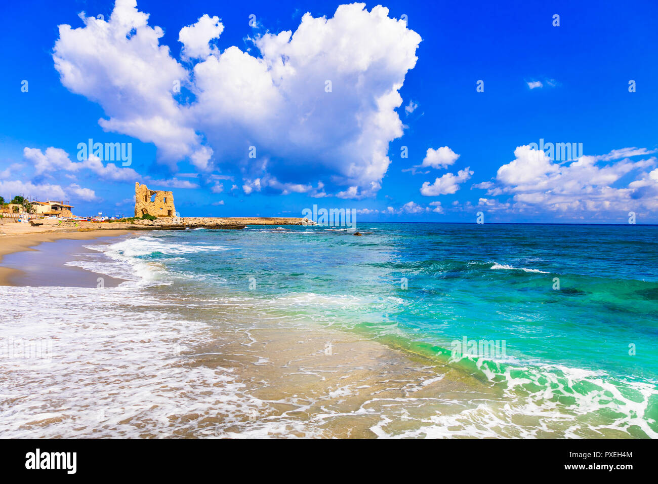 Hermosa playa en Briatico aldea,con vista mar azul y la antigua torre sarracena, Calabria, Italia. Foto de stock