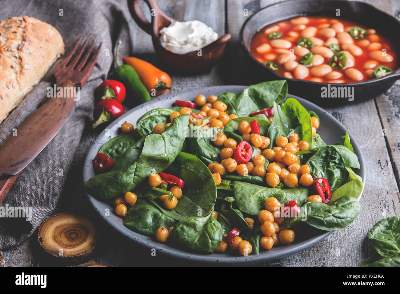 Los garbanzos y verduras con ensalada de hojas de espinaca, la alimentación vegetariana casera saludable, dieta. blanco judías en salsa de tomate Foto de stock