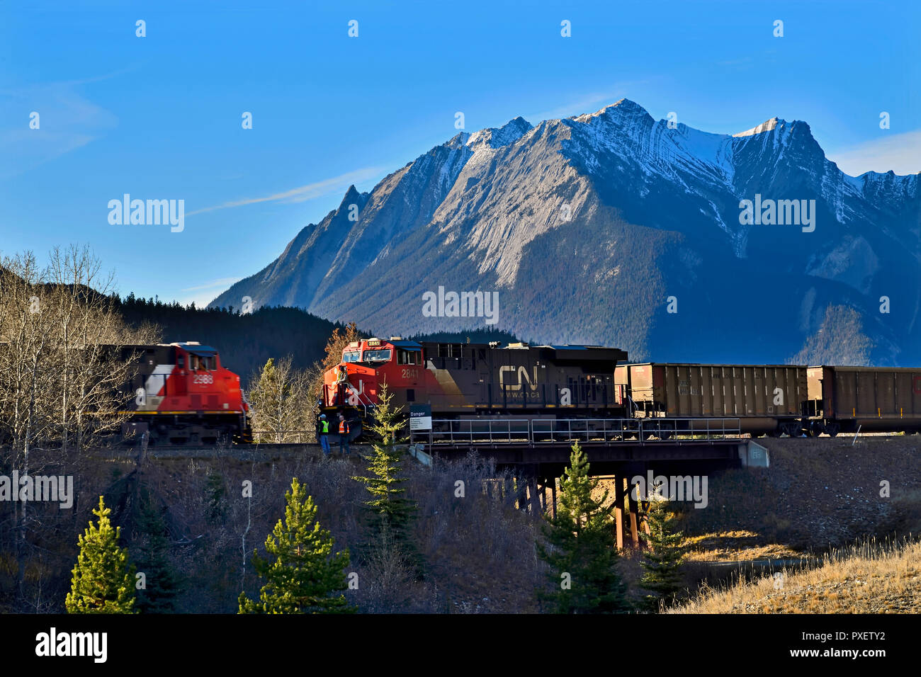 Una imagen horizontal de dos trenes de mercancías pasando a otro sobre un puente de acero en el Parque Nacional de Jasper, Alberta, Canadá. Foto de stock