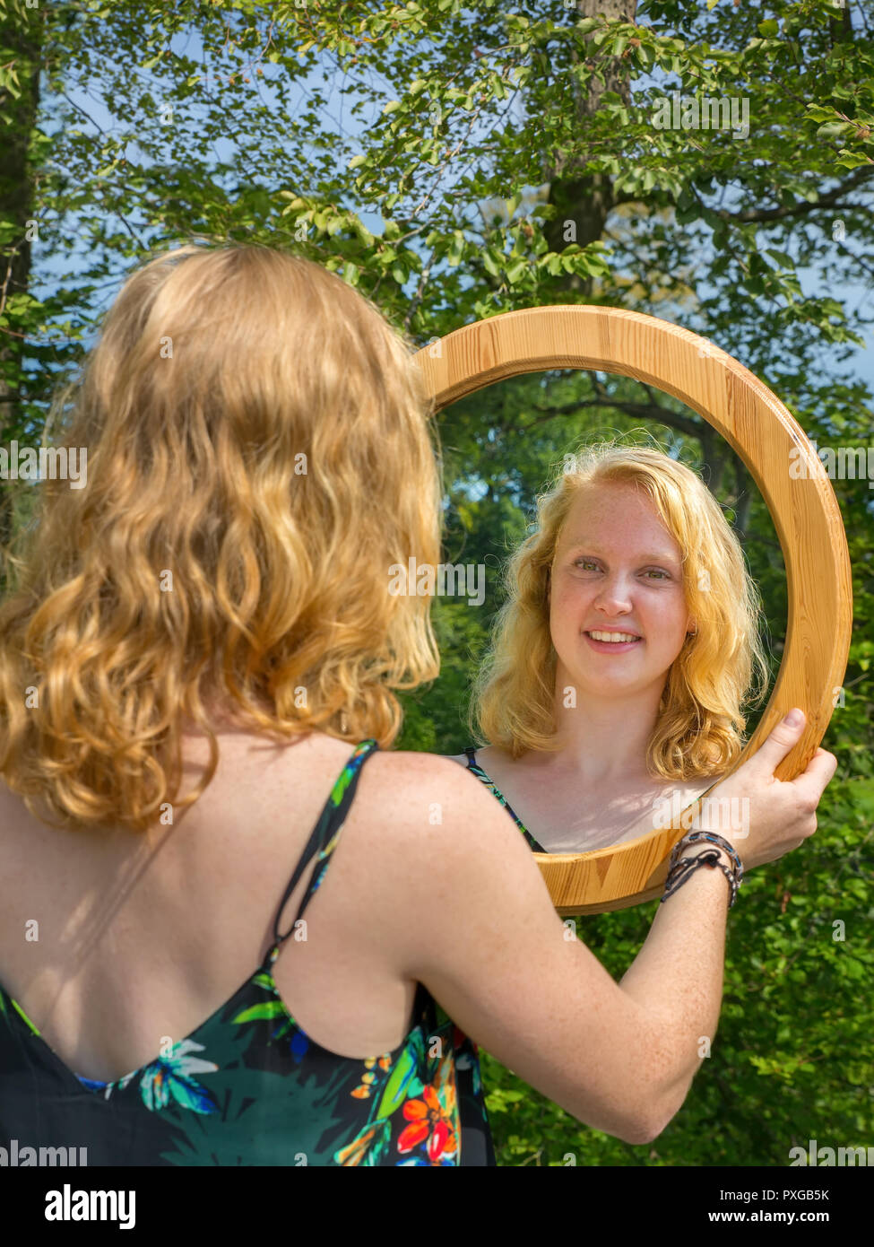 Mujer joven con cabello rojo mirando su reflejo de espejo Foto de stock