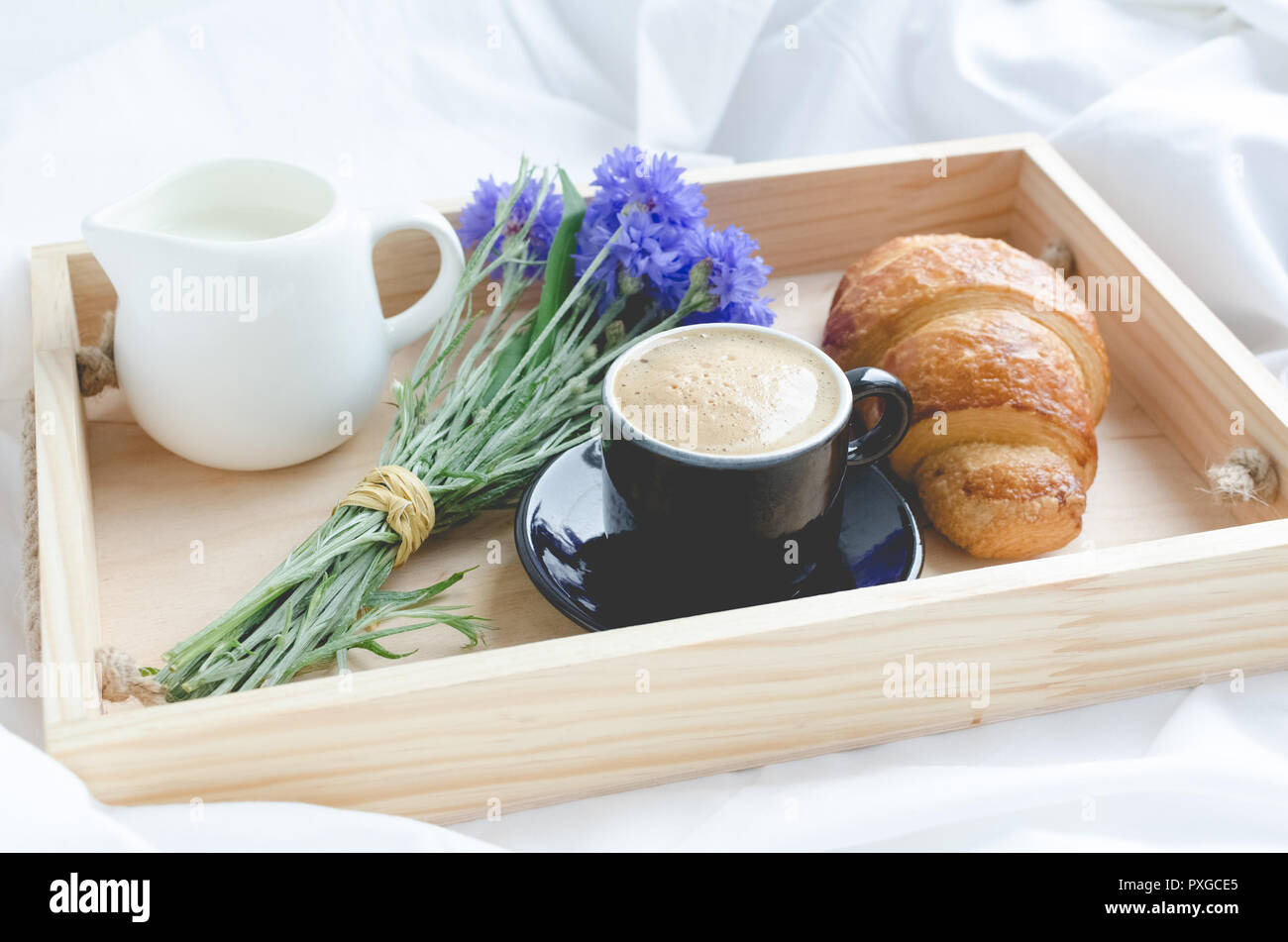 Romántico desayuno en la cama, la bandeja con croissants frescos, taza de  café espresso con leche y ramo de acianos azul. Concepto de buena mañana. E  Fotografía de stock - Alamy
