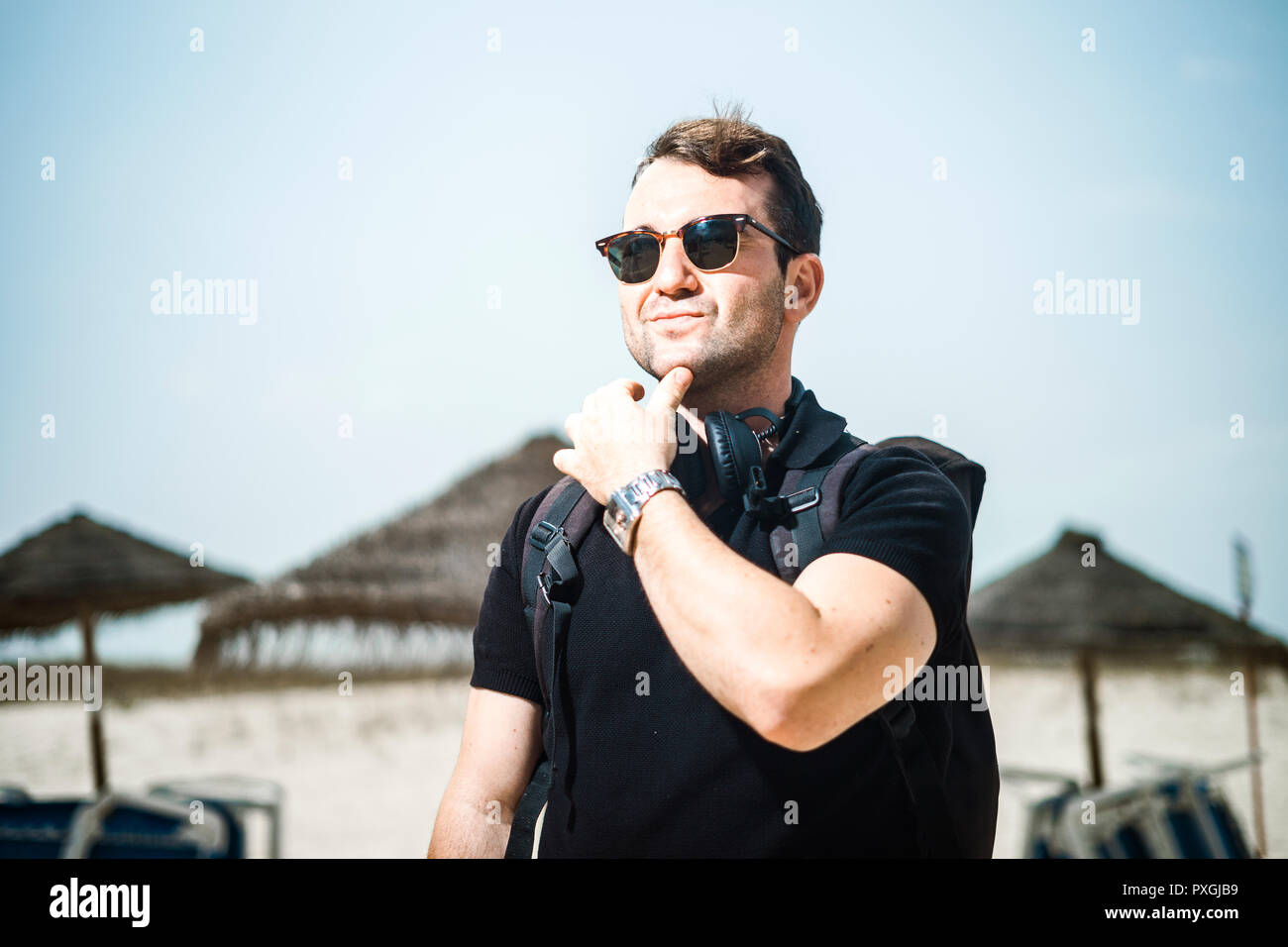 Moda Hombre con gafas de sol, auriculares, reloj y mochila en la playa  Fotografía de stock - Alamy