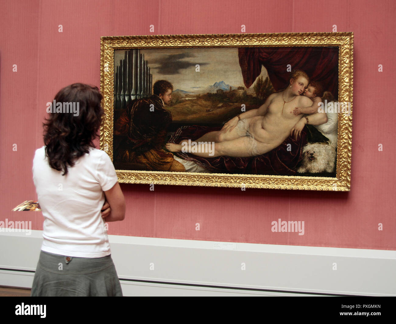 Una mujer se encuentra en una galería de arte admirando una de las pinturas que está colgando en Berlín. Foto de stock