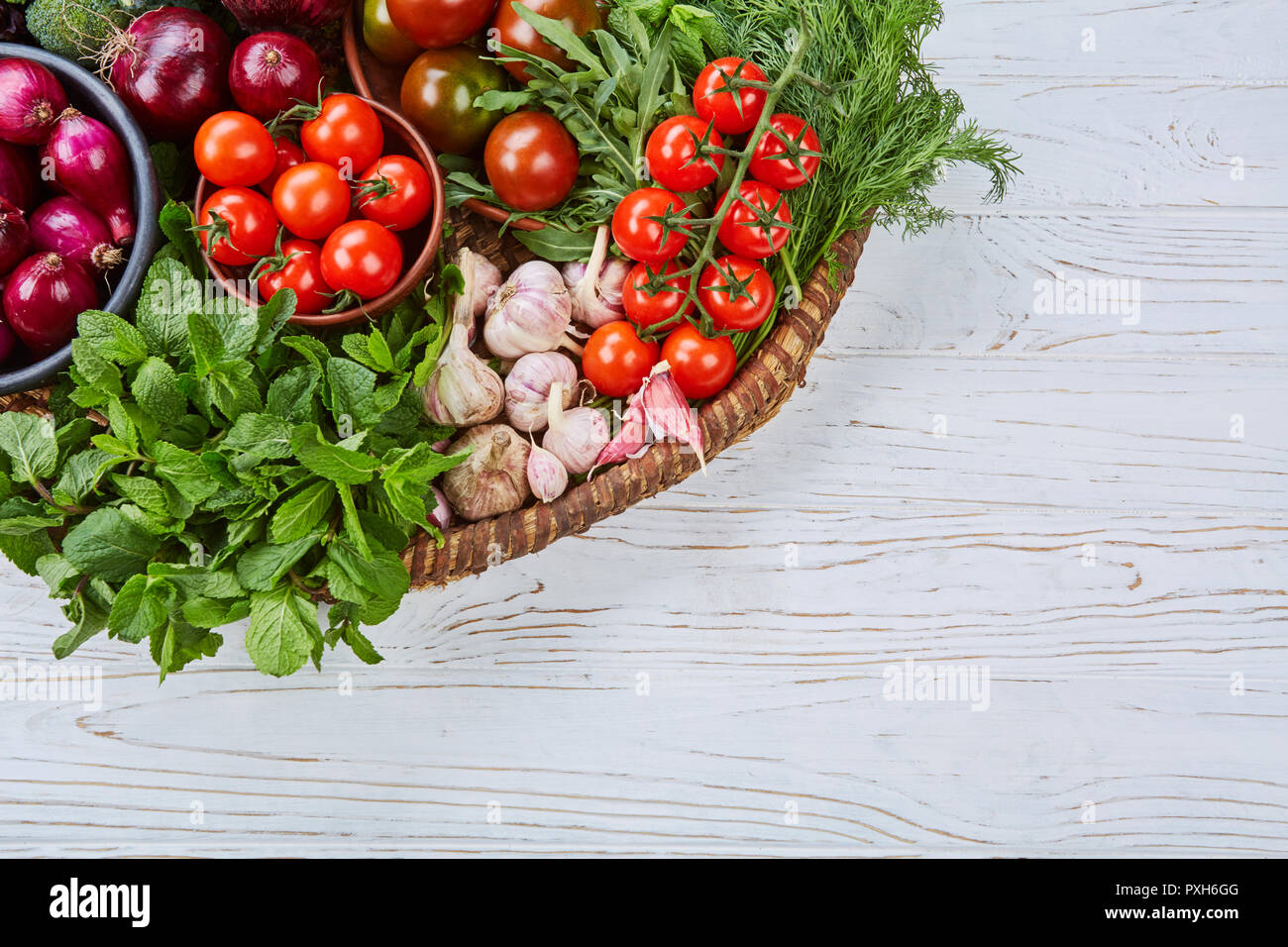 Las verduras surtidas en una canasta grande sobre un mostrador blanco Foto de stock