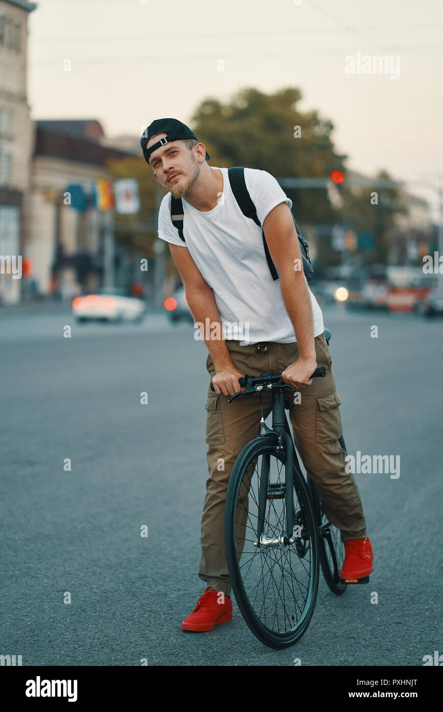 Elegante Hombre con bicicleta para ir a trabajar en la calle. Retrato de  jóvenes varones en ropa casual con mochila caminando por las calles de la  ciudad con elegantes bicicleta. Rojo Fotografía