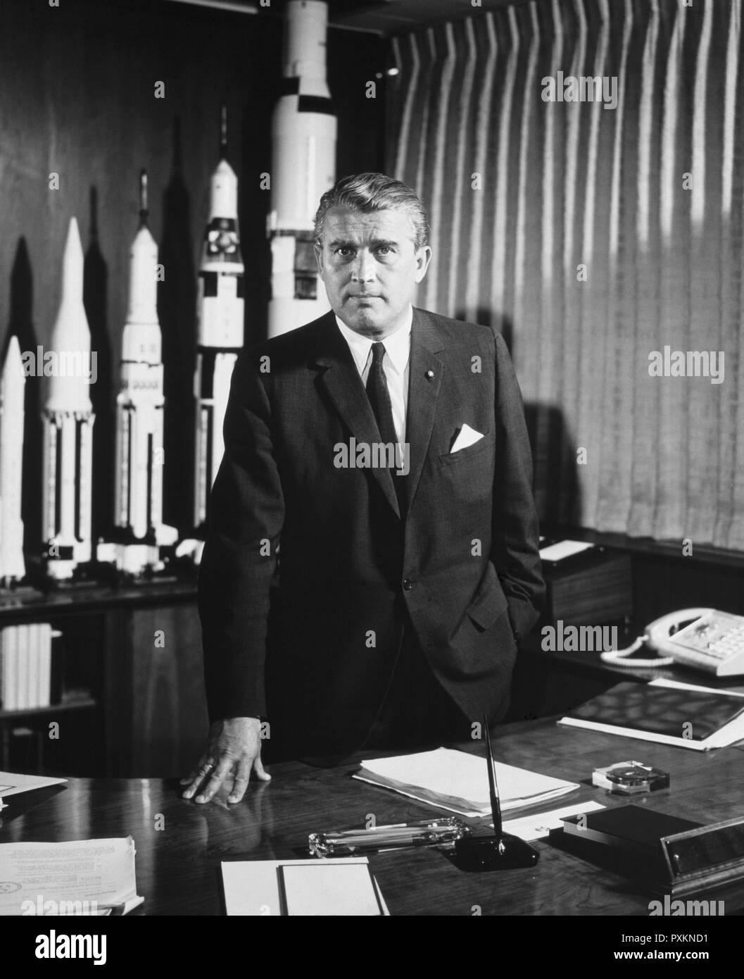 Wernher von Braun (1912-1977), primer director del Centro Marshall de Vuelos Espaciales en Huntsville, Alabama, en su oficina con modelos de cohetes, 18 de mayo de 1964. Foto de stock